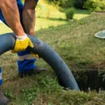 Technicien DCPRO91 réalisant la vidange d'une fosse septique bouchée à l'aide d'un tuyau hydrocureur, intervention en Essonne