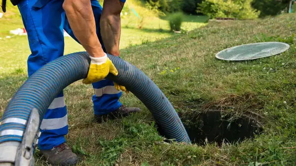Technicien DCPRO91 réalisant la vidange d'une fosse septique bouchée à l'aide d'un tuyau hydrocureur, intervention en Essonne